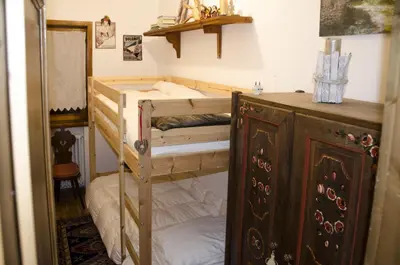 a bedroom with two bunk beds and a wooden cabinet at Casa Salvaniera in San Vito di Cadore