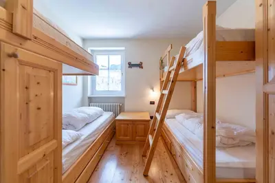two bunk beds in a room with a ladder at Cesa Masè in Pozza di Fassa