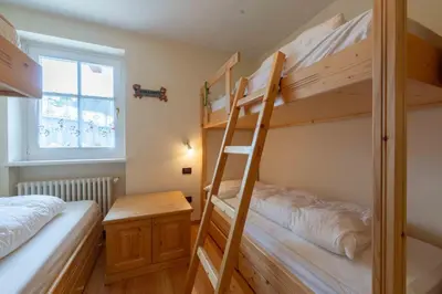 a bedroom with two bunk beds and a desk at Cesa Masè in Pozza di Fassa