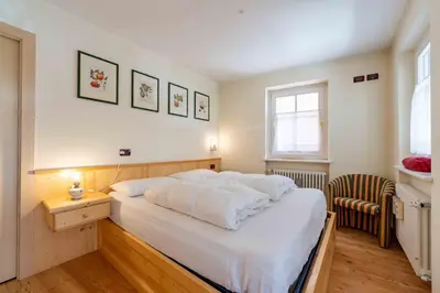 a bedroom with a large white bed and a window at Cesa Masè in Pozza di Fassa