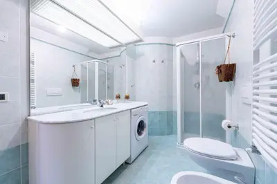 a bathroom with a toilet sink and a washing machine at Cesa Masè in Pozza di Fassa