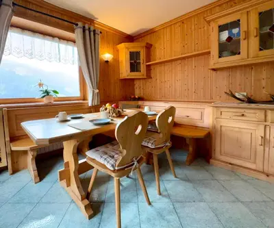 a kitchen with a wooden table and chairs at Antler Apartment in Santa Fosca