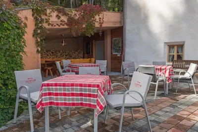 a group of tables and chairs with red and white table cloth at Silentium Dolomites Chalet in Monguelfo