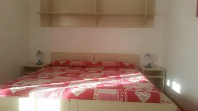 a bedroom with a bed with a red and white comforter at Casa Danoli in Canale San Bovo
