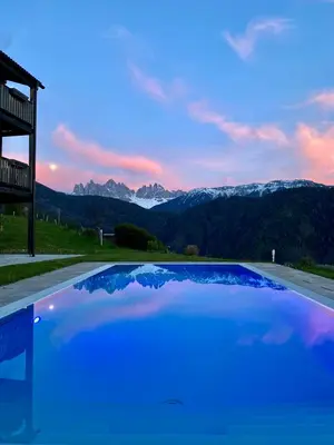 a blue swimming pool with mountains in the background at Oberprantschöllhof - Horse Mountain Stable in Bressanone