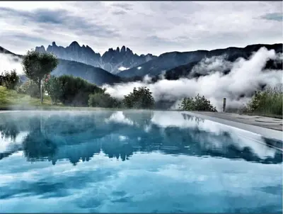 a pool of blue water with mountains in the background at Oberprantschöllhof - Horse Mountain Stable in Bressanone