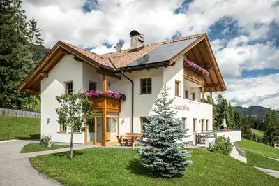 a house with a christmas tree in front of it at Ciasa Odlina in La Villa