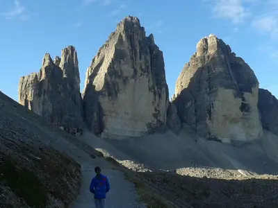 a person walking on a path in front of some rocks at Ciasa Odlina in La Villa