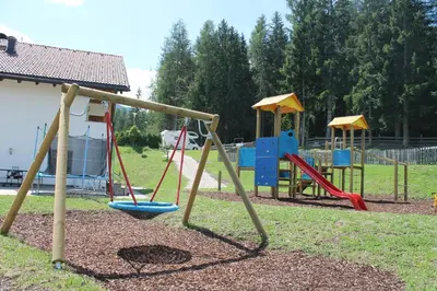a playground with two swings and a slide at Ciasa Odlina in La Villa