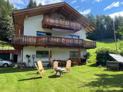 a house with a deck and chairs in the yard at Villa Moos Appartement in Colle Isarco