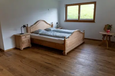 a bedroom with a wooden bed and a window at Villa Moos Appartement in Colle Isarco