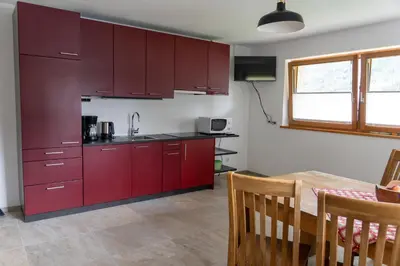 a kitchen with red cabinets and a wooden table at Villa Moos Appartement in Colle Isarco