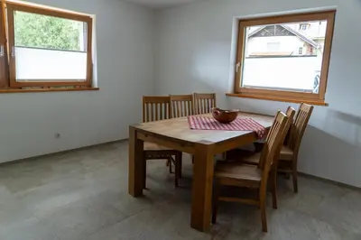 a dining room with a table and chairs and two windows at Villa Moos Appartement in Colle Isarco