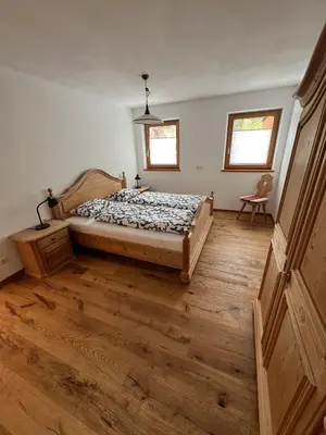 a bedroom with a bed and a wooden floor at Villa Moos Appartement in Colle Isarco