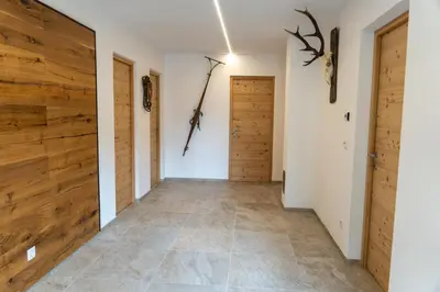 a hallway with wooden doors and tile floors at Villa Moos Appartement in Colle Isarco
