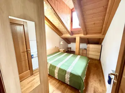 a bedroom with a green bed in a attic at Ciasa De Cin - 10 minutes from Cortina in San Vito di Cadore