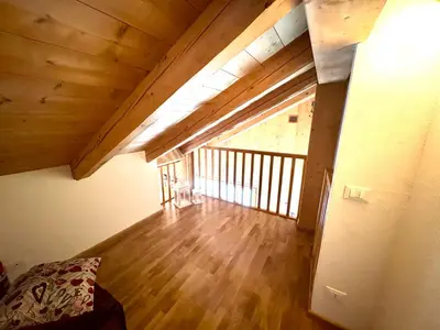 an attic room with a large window and a wooden floor at Ciasa De Cin - 10 minutes from Cortina in San Vito di Cadore