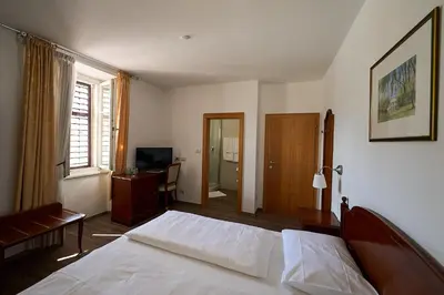 a bedroom with a bed and a desk and a television at Hotel Zur Post in Egna
