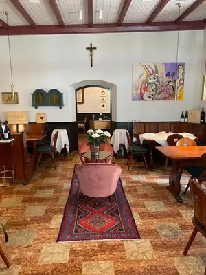 a dining room with tables and a cross on the wall at Hotel Zur Post in Egna