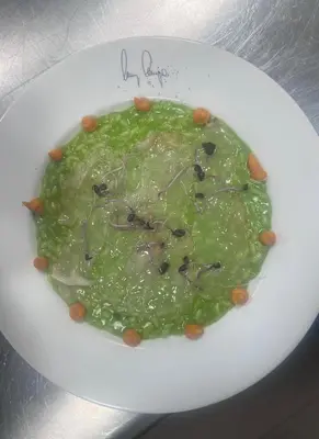 a white plate with a green sauce on a table at Hotel Zur Post in Egna