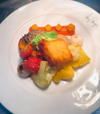 a white plate of food with meat and vegetables at Hotel Zur Post in Egna