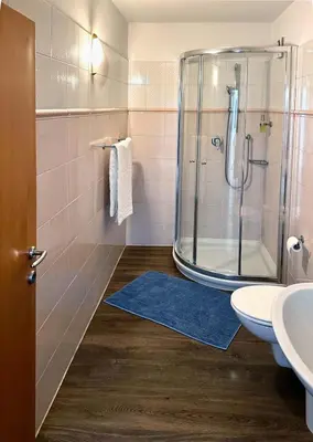 a bathroom with a shower and a blue rug at Hotel Zur Post in Egna