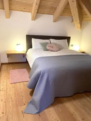 a bedroom with a large bed with a purple blanket at Mansarda Ai Tigli in Castello di Fiemme