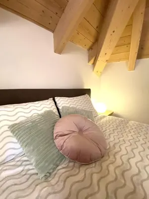 a pink pillow sitting on top of a bed at Mansarda Ai Tigli in Castello di Fiemme