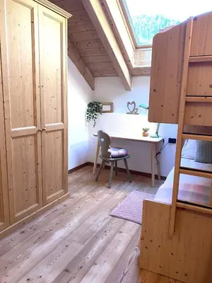 a bedroom with a loft bed and a desk and a table at Mansarda Ai Tigli in Castello di Fiemme