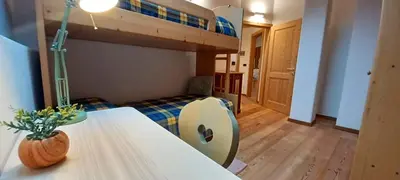 a bedroom with a bunk bed and a table with a vase at Mansarda Ai Tigli in Castello di Fiemme