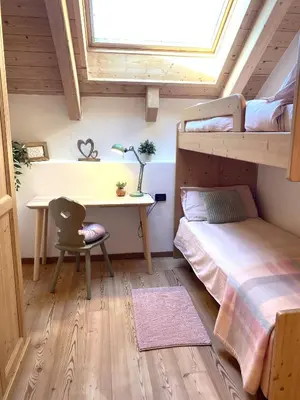 a bedroom with two bunk beds and a desk at Mansarda Ai Tigli in Castello di Fiemme