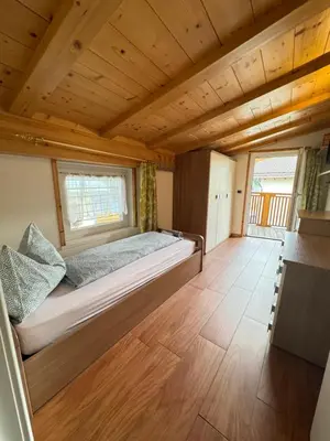 a large bed in a room with a wooden ceiling at Sweet Home in Moena