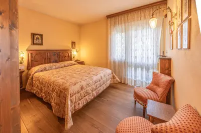a bedroom with a bed and two chairs and a window at Casa Sette, in centro a Cortina d Ampezzo in Cortina dʼAmpezzo