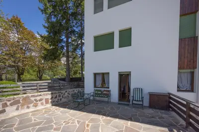 a patio of a white house with two chairs at Casa Ca del Molin, ampia e panoramica in Cortina dʼAmpezzo