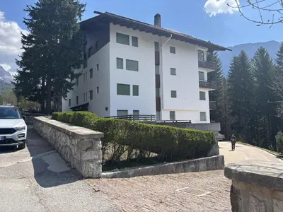 a white building with a car parked in front of it at Casa Ca del Molin, ampia e panoramica in Cortina dʼAmpezzo