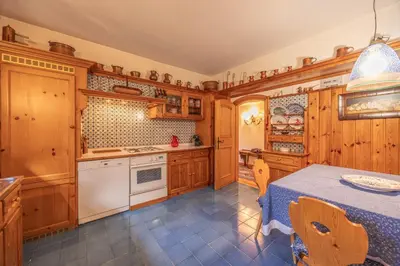 a kitchen with wooden cabinets and a table and chairs at Casa Benedeta, confortevole e panoramica in Cortina dʼAmpezzo