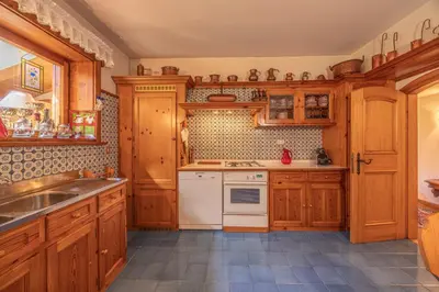 a kitchen with wooden cabinets and a sink at Casa Benedeta, confortevole e panoramica in Cortina dʼAmpezzo