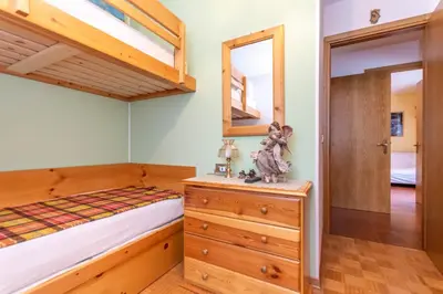 a bedroom with a bunk bed and a dresser with a mirror at La Finestra sul Civetta in Alleghe