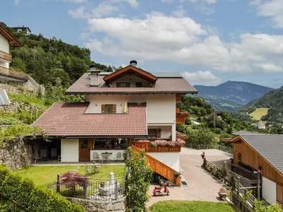 a house on a hill with mountains in the background at Marxhof in Barbiano