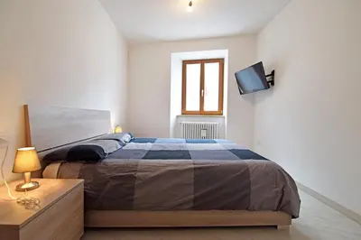 a bedroom with a bed and a tv on a wall at Casa Angelini in Castello di Fiemme