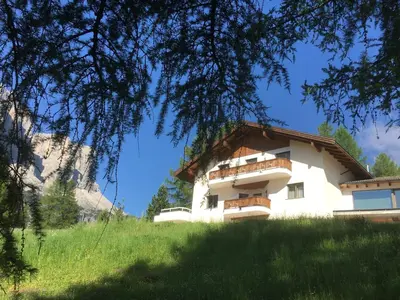 a building on a hill with a tree at Ciasa Roenn in Colfosco