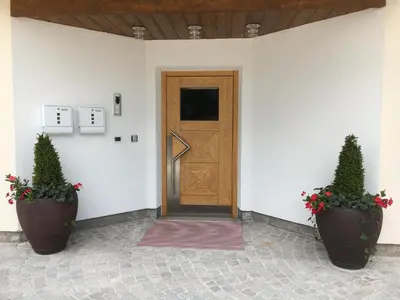 a door in a white building with two potted plants at Ciasa Roenn in Colfosco