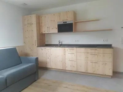 a kitchen with wooden cabinets and a couch and a microwave at Mitterhofer Appartements in Villandro
