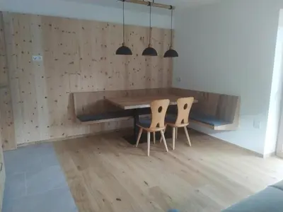 a dining room with a wooden table and two chairs at Mitterhofer Appartements in Villandro