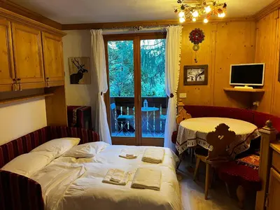 a bedroom with a bed and a desk and a window at Appartamento Lagazuoi nel cuore delle Dolomiti in Livinallongo del Col di Lana