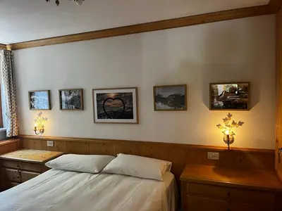 a bedroom with a bed and a table and a window at Appartamento Lagazuoi nel cuore delle Dolomiti in Livinallongo del Col di Lana