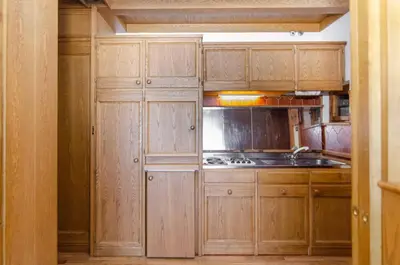 a kitchen with wooden cabinets and a sink and a stove at Comfort loft, appartamento centrale con giardino in Cortina dʼAmpezzo