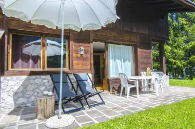 a patio with a table and chairs and an umbrella at Comfort loft, appartamento centrale con giardino in Cortina dʼAmpezzo