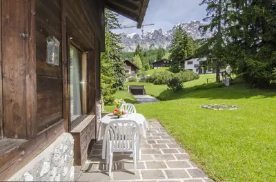 a table and chairs on the porch of a house at Comfort loft, appartamento centrale con giardino in Cortina dʼAmpezzo