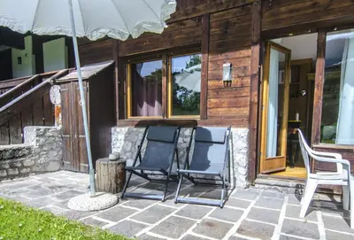 two chairs sitting on a patio with an umbrella at Comfort loft, appartamento centrale con giardino in Cortina dʼAmpezzo